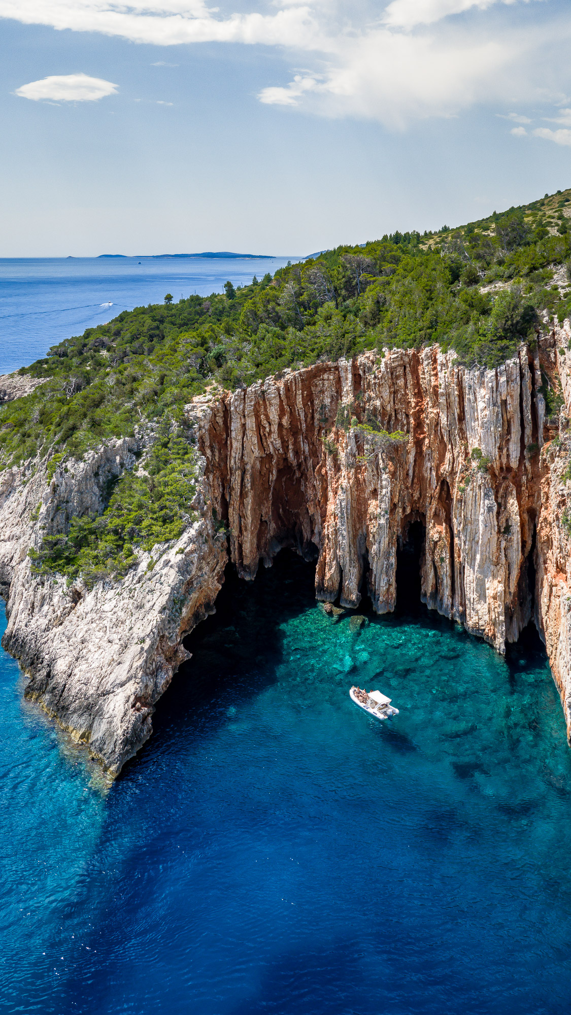 Iron-red cliffs at Red Rocks with a speedboat drifting below